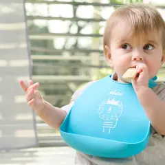 Bambino con bavaglino blu che mangia un biscotto, un esempio di autosvezzamento come funziona.