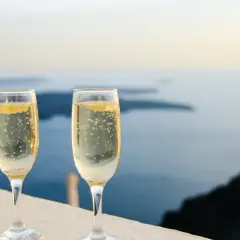 Zwei Gläser Champagner mit Bläschen vor einer Meereslandschaft. Die Frage, wie lange ist Champagner haltbar, beschäftigt Genießer.