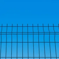 Siatka ogrodzeniowa na tle błękitnego nieba. Widać jej regularną strukturę i określoną wysokość.
