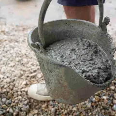 Secchio pieno di cemento fresco, pronto per essere utilizzato. Imparare come fare il cemento è fondamentale per ogni progetto di costruzione.