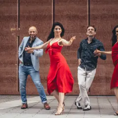 Dwie pary tańczą gorący zouk. Kobiety w czerwonych sukienkach, mężczyźni w eleganckich strojach.