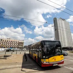 Autobus MZA Warszawa na tle wieżowca Novotel i budynków mieszkalnych.
