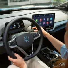 Interior de un coche eléctrico Volkswagen. Se ve el volante, la pantalla táctil central y la palanca de cambios. La dirección asistida progresiva se adapta a la velocidad.