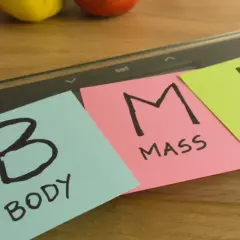 Na wadze leżą karteczki z napisem "BODY MASS INDEX". Dążenie do prawidłowego BMI to klucz do zdrowia.