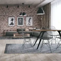 Surowy, betonowy sufit w stylu loft nadaje wnętrzu industrialnego charakteru. Ceglana ściana, grafiki i metalowe meble dopełniają ten surowy klimat.