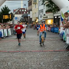 Läufer und Radfahrer beim Stadtlauf Bergisch Gladbach. Zuschauer jubeln am Streckenrand.