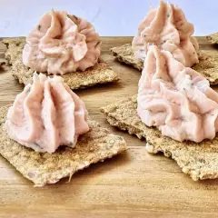 Petites bouchées de rillettes de jambon onctueuses sur des crackers croustillants, prêtes à être dégustées.