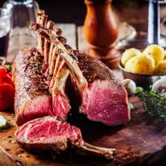 Un succulent carré d'agneau rôti, accompagné de tomates cerises, de pommes de terre et d'une touche d'herbes fraîches.