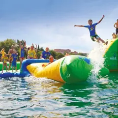 Des enfants s'amusent dans un aquapark gonflable près de Paris, un garçon saute dans l'eau.