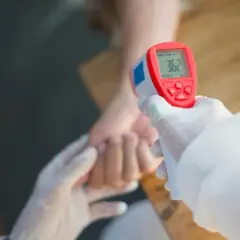 Rękawiczki i termometr bezdotykowy mierzą temperaturę, która może wskazywać na przewlekły stan podgorączkowy i zmęczenie.