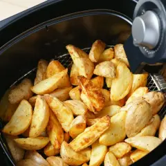 Patate a spicchi dorate e croccanti appena sfornate nella friggitrice ad aria.