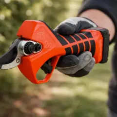 Pomarańczowy sekator Felco 2e, trzymany w rękawicy, gotowy do przycinania gałęzi.