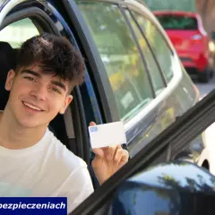 Uśmiechnięty młody kierowca oc pokazuje kartę ubezpieczenia.