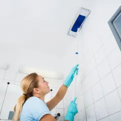 Femme nettoyant le plafond avec une raclette. Le sens de pose du lambris PVC au plafond est important pour un résultat impeccable.