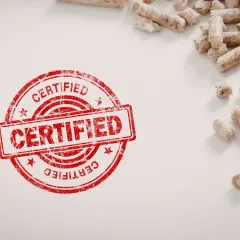 Certyfikowany pellet, potwierdzający, że pellet jest odnawialnym źródłem energii, leży obok czerwonego stempla.
