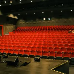 Widok na puste czerwone fotele w sali kinowej lub teatralnej.