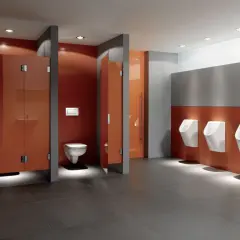 Moderne schul toilette mit orangen Kabinen und Reihen von Urinalen.