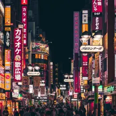 Nocna ulica Tokio z neonowymi szyldami i tłumem ludzi.