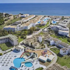 Widok z lotu ptaka na kompleks hotelowy z basenami, zjeżdżalniami i placem zabaw, blisko plaży. Wiele budynków, zieleni i morza. Idealne miejsce na wakacje, zgodnie z labranda sandy beach resort opinie.