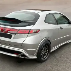 Srebrny Honda Civic VIII z czarnym spoilerem na klapie bagażnika i przyciemnianymi felgami.