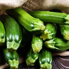 Frische, grüne Zucchini quellen aus einem Jutesack. Diese gesunde Gemüsesorte ist perfekt für leichte und nahrhafte Gerichte.
