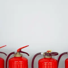 Vier rote Feuerlöscher stehen nebeneinander. Sie enthalten ABC-Pulver, das bei Bränden nützlich ist, aber nicht giftig ist.