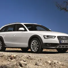 Białe Audi A4 B8 Allroad quattro na kamienistej drodze pod błękitnym niebem.