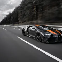 Czarny Bugatti Chiron Super Sport z pomarańczowymi pasami pędzi po pustej autostradzie.