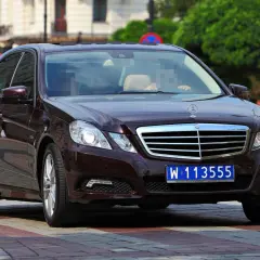 Ciemnobrązowy Mercedes z niebieską tablicą rejestracyjną W 113555, typową dla pojazdów dyplomatycznych w Polsce.