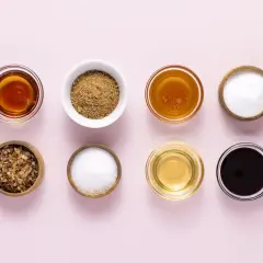Verschiedene Schalen mit süßen Flüssigkeiten und Pulvern, die als zucker ersatz dienen könnten: Honig, brauner Zucker, weißer Zucker und mehr.