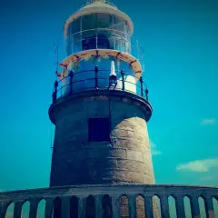 El faro de Corrubedo se alza imponente bajo un cielo azul intenso.