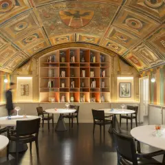 Interni eleganti con soffitto affrescato, libreria a vista e tavoli apparecchiati, un'atmosfera che evoca le stelle Michelin di Perbellini.