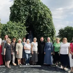 Grupa osób z księdzem i siostrą zakonną przy kapliczce Matki Bożej. Odnowa w duchu świętym zagrożenia, nadzieja w wierze.