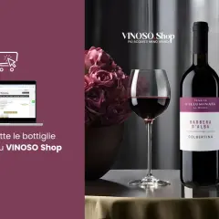 Un bicchiere e una bottiglia di Dolcetto d'Alba, uno dei vini piemontesi rossi più apprezzati, su un tavolo elegante. Acquista online su VINOSO Shop.