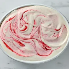 Kremowe lody jogurtowe z malinową spiralką, wyglądające jak dzieło sztuki.