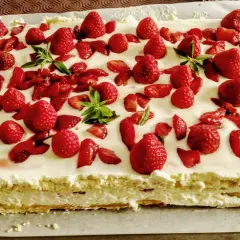 Un délicieux entremet fraise, garni de fruits rouges frais et de feuilles de menthe, sur une base crémeuse.