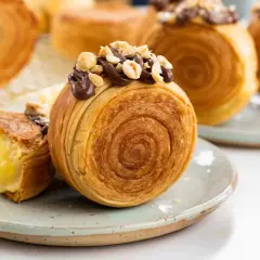 Deliziosi dolci francesi, croissant a spirale ripieni di crema e guarniti con cioccolato e nocciole.