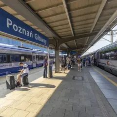 Peron na dworcu Poznań Główny z pociągami i pasażerami.