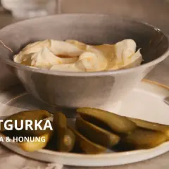 En skål med krämig smetana och honung, serverad med saltgurka. En oväntad men utsökt kombination.