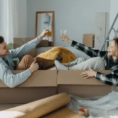 Pareja brindando dentro de cajas, listos para mudarse. ¡Qué alivio que mi casero quiere hacer obras y nos da esta oportunidad!