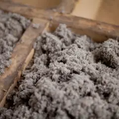 Gros plan sur de la ouate de cellulose grise, un isolant qui peut présenter un danger en cas de mauvaise manipulation.