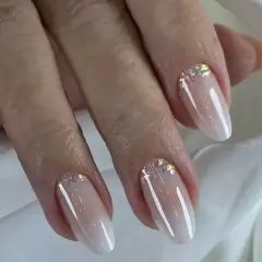 Elegancki manicure baby boomer z subtelnymi drobinkami brokatu na paznokciach.
