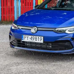 Niebieski Volkswagen z rejestracją PY 49819 stoi przed kolorowym płotem.