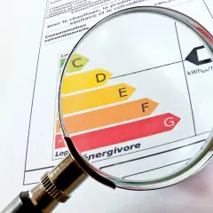 Loupe sur un diagnostic de performance énergétique (DPE). La classification de A à G, indiquant une interdiction location, est examinée.