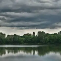 Ciemne chmury zapowiadają biały szkwał nad spokojną taflą jeziora.