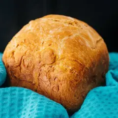 Chleb z airfryer, pachnący i złocisty, owinięty w turkusowy ręcznik. Idealny na śniadanie.