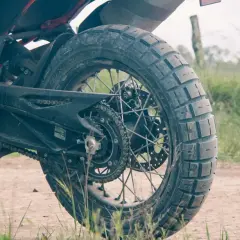 Tylne koło motocykla z oponą Pirelli Scorpion Rally STR na szutrowej drodze, gotowe na przygodę.