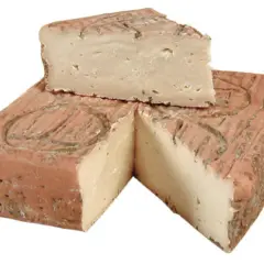 Un pezzo di taleggio bergamasco, con la crosta rosata e la pasta chiara e compatta, tagliato a spicchi.
