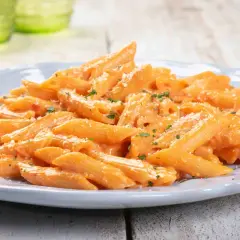 Penne cremose con salsa rosa, un piatto gustoso e paste facili da fare, guarnito con parmigiano e prezzemolo.