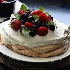Pyszna beza mokra w środku, udekorowana świeżymi truskawkami, borówkami i jeżynami.